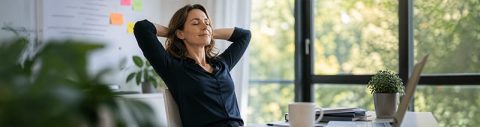 Leadership Training zu Führung und Persönlichkeit: Frau lehnt sich entspannt im Bürostuhl zurück und stärkt Selbstwirksamkeit, Resilienz und innere Stärke