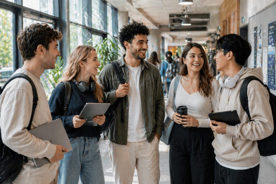 Systemische Coaching-Ausbildung in Berlin für Ihren Weg zum systemischen Coach Systemische Coaching-Ausbildung in Berlin: junge Auszubildende unterhalten sich gut gelaunt in einem Flur einer Schule oder Universität